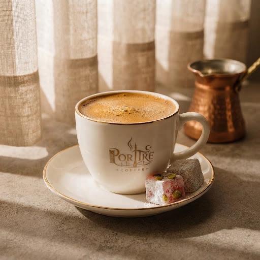 PortreCoffee cup of Turkish coffee with Turkish delight and a copper cezve in the background